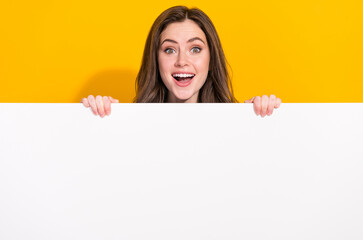 Photo of funky astonished person hide behind empty space blank open mouth isolated on yellow color...