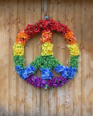 A colorful peace sign made of multi-colored flowers hangs on a wooden wall in Woodstock, NY.   - obrazy, fototapety, plakaty