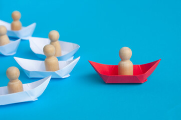 Leadership concept - People wooden figure on red paper ship origami leading the rest of the people...