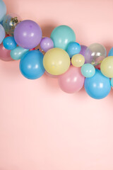 A soft pastel balloon garland against a light baby pink background