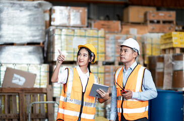 Asian supervisor talking about job with worker in warehouse and they compares checklist with tablet data