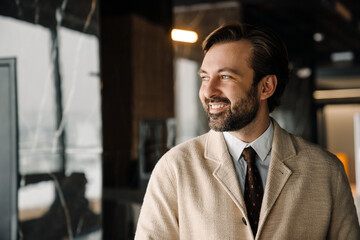Fototapeta premium Portrait of happy smiling bearded businessman in jacket looking aside