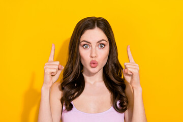 Portrait of impressed pretty person direct fingers up empty space isolated on yellow color background