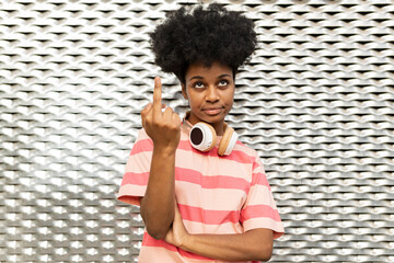 Young woman gesturing middle finger in front of wall