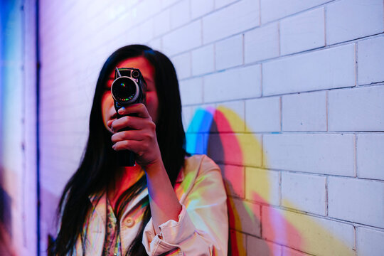 Young woman with long hair filming through video camera