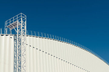 A modern hangar with a staircase to the roof on a blue sky background. Copy space