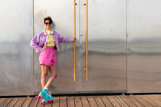 Smiling woman wearing roller skates standing by door