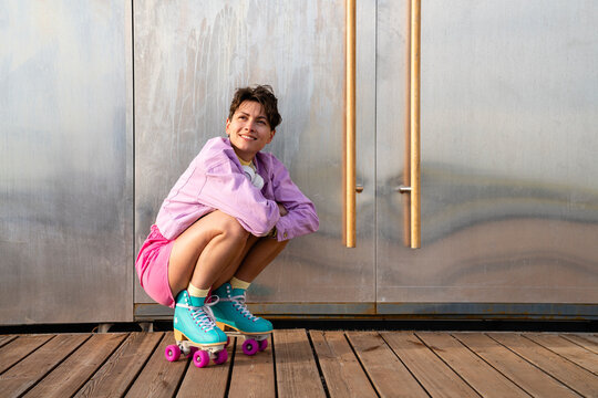 Smiling woman with roller skates day dreaming by door