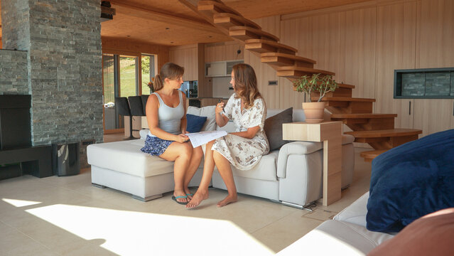 CLOSE UP: Two young women sitting on a sofa and consulting interior house design
