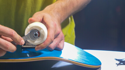 CLOSE UP: Young man's hands mounting wheels on trucks of a new skateboard setup