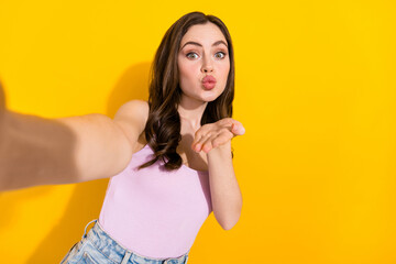 Photo of lovely pretty girl make selfie arm palm send air kiss you isolated on yellow color...