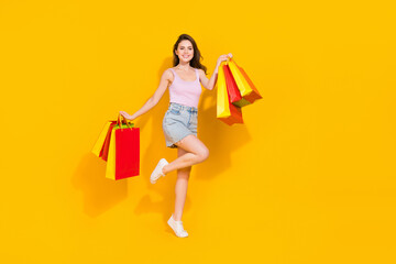 Full length photo of dreamy sweet woman wear pink top holding shoppers isolated yellow color background