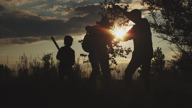Silhouettes of old grandparents and little girl together planting tree in field at sunset outdoors. Human saving planet Earth health : reforestation works, environmental activity, forest ecology help