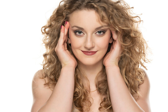 Attractive blonde woman with curly beautiful hair tightens her face with the white background