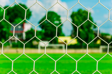 Fototapeta premium Nets of a soccer field.Empty soccer goal on a soccer green lawn field.Bright summer day.Selective focus.Closeup.