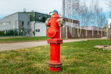 Single red fire hydrant on green lawn.In a background factory.Autumn,spring,summer day.