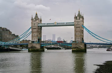 Foto op Plexiglas De London Tower Bridge met een iconische rode bus erop en de Theems op de voorgrond. © Frema