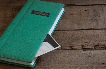 old photograph album on wooden table with black and white photo loose