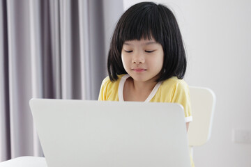 little asian girl student study online using laptop computer at home