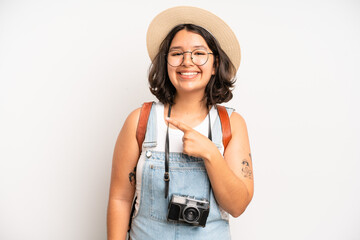 hispanic pretty girl smiling cheerfully, feeling happy and pointing to the side. photographer concept