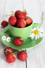 ripe strawberries from the garden in a green mug with white chamomile, summer 
