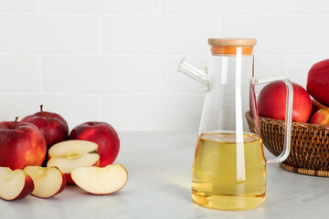 Natural apple vinegar and fresh fruits on white marble table
