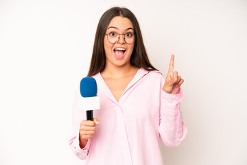 hispanic pretty woma smiling and looking friendly, showing number one. journalist with a microphone
