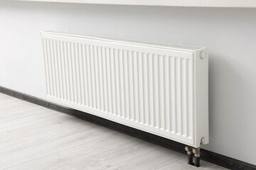Modern radiator on white wall in room. Central heating system