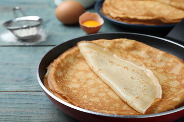 Delicious thin pancakes on blue wooden table, closeup
