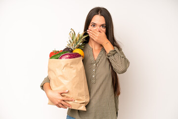 hispanic pretty woma feeling confused and puzzled, showing you are insane. market vegetables bag...