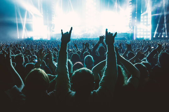 A lot of people raised up hands at the concert event. Fans arms against the stage light.