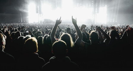 Obraz premium A lot of people raised up hands at the concert event. Fans arms against the stage light.