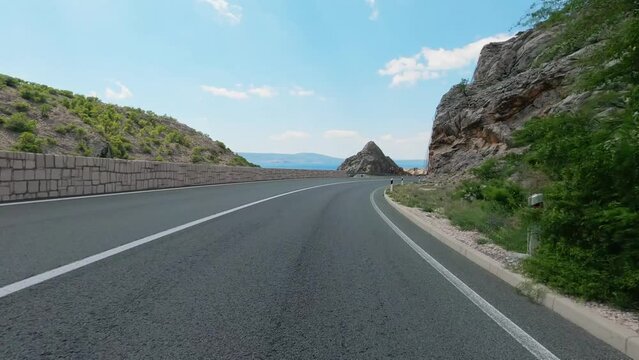 POV of driving over the asphalt of the coastal road south of Rijeka, Croatia overlooking the Adriatic Sea