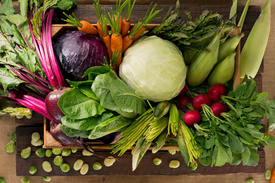 Top view of a box full of fresh vegetables on a marble table.