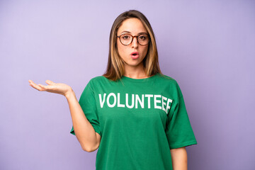 pretty caucasian woman looking surprised and shocked, with jaw dropped holding an object. volunteer...