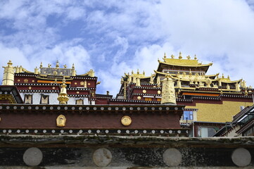 The colorful rooflines of the buildings at the Songzanlin monastery in Shangri-La, China - contrasting against the clear blue sky and adorned with many flags