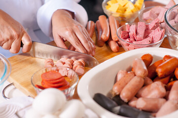Obraz na płótnie Canvas Hands cutting a variety of sausages and cold cuts meat, preparing ingredients to make fiambre, Guatemalan dish of all saints day.