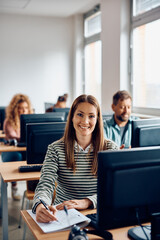 Happy woman taking notes during computer class and looking at camera.