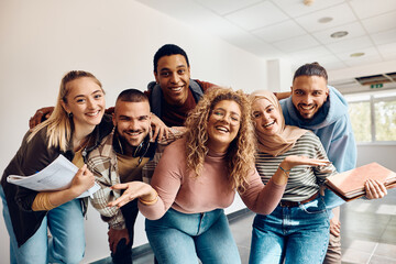 Multi ethnic group of happy college friends have fun in hallway and looking at camera.