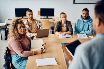 College student and her friends listening teacher's lecture in classroom.