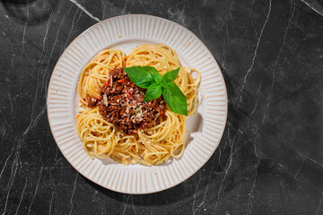 Delicious mouth-watering classic Italian spaghetti pasta with tomato sauce, parmesan cheese and basil on a plate on a white table. Top view, horizontal