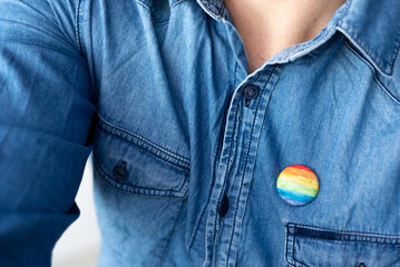 plate, multicolored flag badge that represents LGTBIQ pride on the chest of a person, man. closeup...
