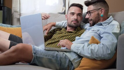 Male caucasian gay couple using laptop computer at home. High quality 4k footage - Powered by Adobe