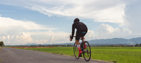 Professional cyclist in cycling training suit against green nature blur background Healthy fitness...