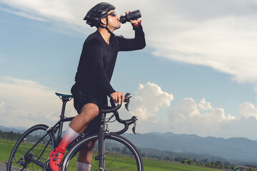 Male cyclist drinking water from a water bottle on a bicycle