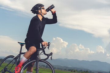 Male cyclist drinking water from a water bottle on a bicycle