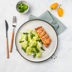 Grilled salmon fillet with green beans and lettuce leaves on a plate. Delivery of fresh, healthy food, catering. Light background.