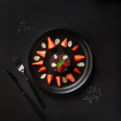 cooked brown rice berry rice (non-glutinous purple rice) with berries on the black plate on the black table