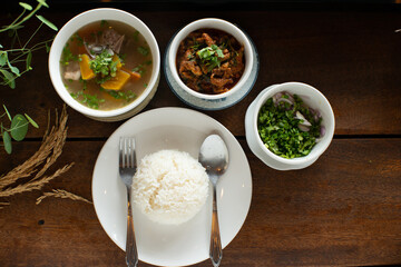 Food set white rice pumpkin soup spicy pork and slice mixed vegetable on wooden table with spoon fork