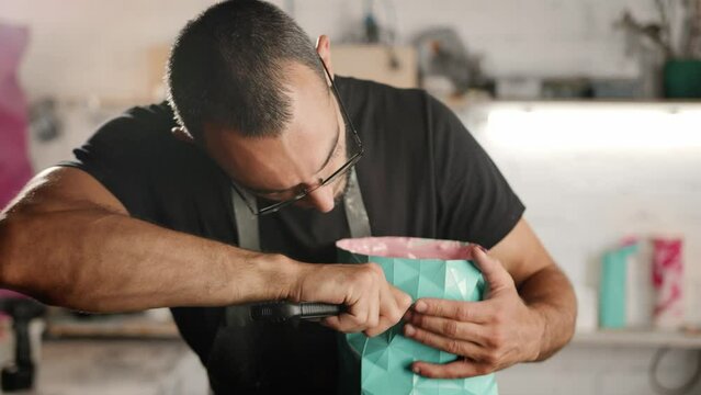 A male craftsman creates a decorative product with his own hands. Handmade, workshop. Creative chaos.